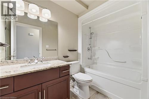 Bathroom featuring a white tub/shower combination, dark wood-finish vanity with a light-toned countertop, and chrome fixtures - 29 Archdeacon Clark Trail, Hamilton, ON 