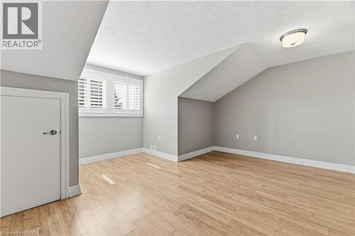 Room with wood-finish flooring, a sloped ceiling, and a flush-mount ceiling light fixture - 29 Archdeacon Clark Trail, Hamilton, ON 