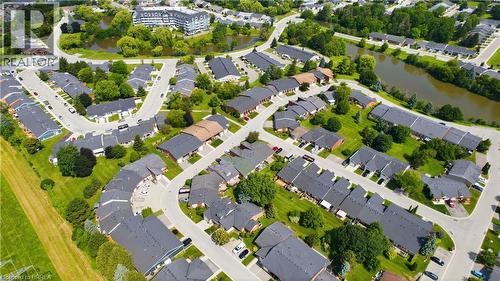Aerial perspective of a developed residential area featuring various housing units, mature trees, and a visible body of water - 29 Archdeacon Clark Trail, Hamilton, ON 