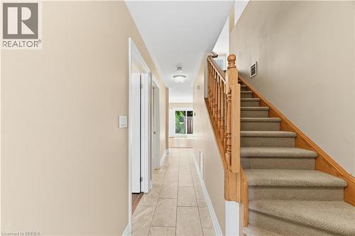 Entryway featuring a carpeted staircase with wood banister and balusters - 29 Archdeacon Clark Trail, Hamilton, ON 