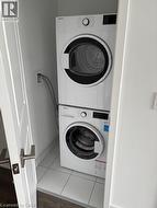 Dedicated laundry closet featuring a stackable washer and dryer unit and tile flooring - 