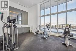 Fitness room featuring expansive floor-to-ceiling windows, rubber flooring, and recessed lighting - 