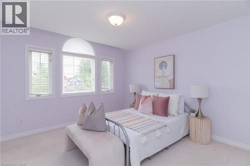 Bedroom featuring soft wall color, broadloom flooring, and a unique arched window - 566 Avignon Place, Waterloo, ON 