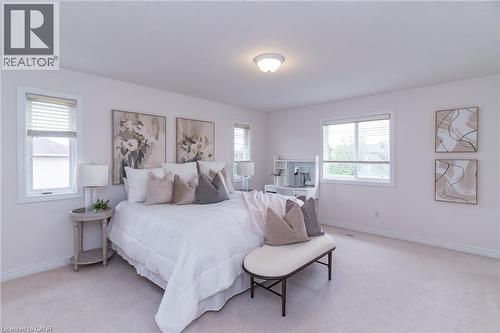 Carpeted bedroom featuring white baseboards, light wall paint, and multiple windows with blinds - 566 Avignon Place, Waterloo, ON 