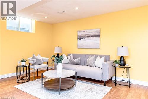 Living area featuring wood-finish flooring, recessed lighting, and a prominent egress window - 566 Avignon Place, Waterloo, ON 