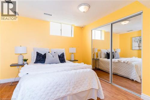 Bedroom featuring wood-finish flooring, a ceiling-mounted light fixture, and a window - 566 Avignon Place, Waterloo, ON 
