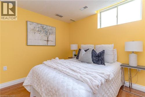 Bedroom featuring light yellow walls, wood-finish flooring, white baseboards, and a high-set window - 566 Avignon Place, Waterloo, ON 