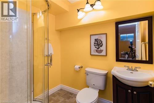 Bathroom featuring a curved glass shower enclosure with tiled surround, a dark wood-finish vanity with an integrated sink, and a framed mirror - 566 Avignon Place, Waterloo, ON 