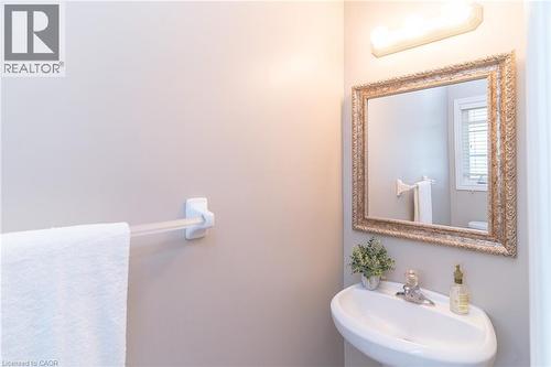 Pedestal sink with single-handle faucet, ornate framed mirror, and wall-mounted vanity lighting - 566 Avignon Place, Waterloo, ON 