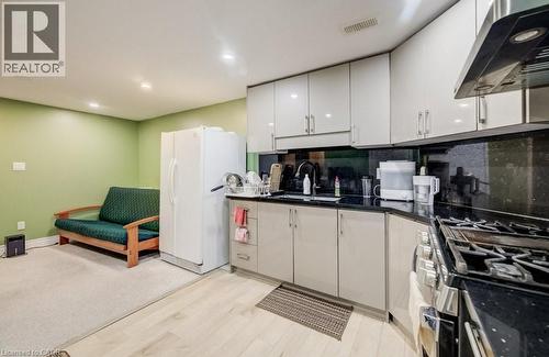 Compact kitchen featuring light-toned cabinetry, dark countertops, a stainless steel range hood, and a gas range - 123 Forest Edge Trail, Kitchener, ON 