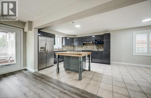 Modern kitchen featuring dark cabinetry, stainless steel appliances, and a mosaic tile backsplash - 123 Forest Edge Trail, Kitchener, ON - Indoor Photo Showing Kitchen