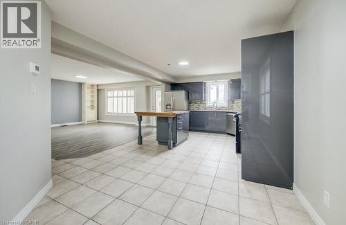 Open-concept kitchen and living area featuring tile flooring, a central island with wood-finish countertop, dark cabinetry, and stainless steel appliances - 123 Forest Edge Trail, Kitchener, ON - Indoor