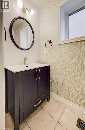 Modern vanity featuring a white countertop, gold-finish faucet, and a circular mirror with a dark frame - 123 Forest Edge Trail, Kitchener, ON - Indoor Photo Showing Bathroom