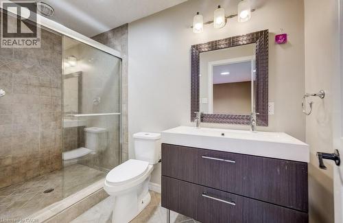 Modern bathroom featuring a glass-enclosed shower with tile surround, a contemporary vanity with an integrated sink, a dark wood-finish cabinet with drawer storage, and a decorative framed mirror - 123 Forest Edge Trail, Kitchener, ON - Indoor Photo Showing Bathroom