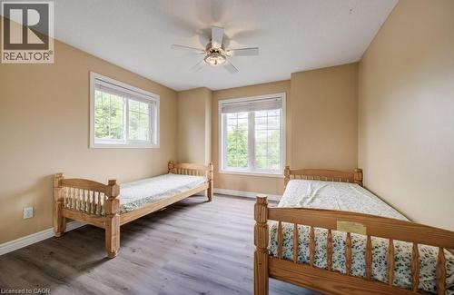 Room featuring wood-finish flooring, two large windows with white trim, and a ceiling fan with integrated lighting - 123 Forest Edge Trail, Kitchener, ON - Indoor Photo Showing Bedroom