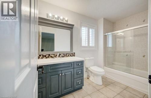 Bathroom featuring a vanity with a white countertop, mosaic tile backsplash, framed mirror, and a four-bulb light fixture - 123 Forest Edge Trail, Kitchener, ON - Indoor Photo Showing Bathroom