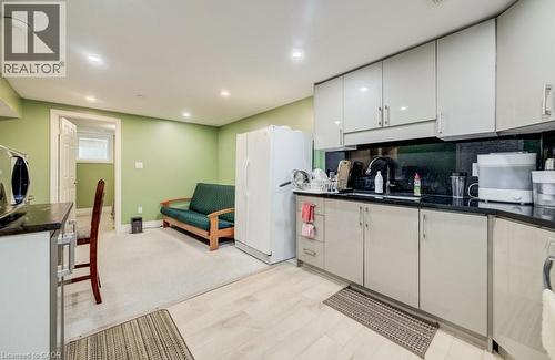 Compact kitchen area featuring light-toned cabinetry, dark countertops, and a full-size refrigerator - 123 Forest Edge Trail, Kitchener, ON - Indoor