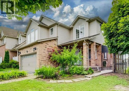 Two-story residence featuring brick and siding exterior, an integrated garage with overhead door, a covered porch entry, and established landscaping - 123 Forest Edge Trail, Kitchener, ON - Outdoor