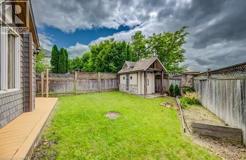 Expansive backyard featuring a manicured lawn, a detached storage shed with architectural detailing, and a wooden deck - 123 Forest Edge Trail, Kitchener, ON - Outdoor