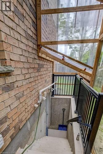 Brick exterior with a clear panel enclosure and a concrete stairwell featuring black metal railings - 123 Forest Edge Trail, Kitchener, ON - Outdoor With Exterior