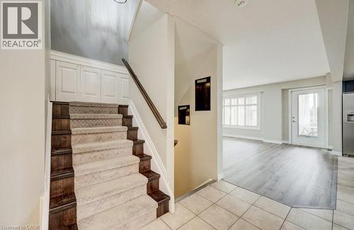 Entryway featuring a carpeted staircase with wood-finish risers and handrail, neutral tile flooring, and integrated wall paneling - 123 Forest Edge Trail, Kitchener, ON - Indoor Photo Showing Other Room