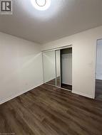 Interior room featuring wood-finish flooring, white walls, and white baseboards - 