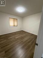 Room featuring wood-finish flooring, a window with horizontal blinds, and a flush-mount ceiling light fixture - 