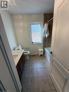Bathroom featuring a single window, tiled flooring, wood-finish vanity with countertop, and a shower-tub combination with tiled surround - 
