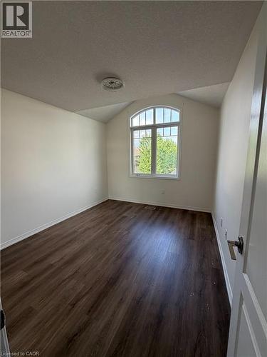 Room featuring a prominent arched window, wood-finish flooring, white baseboards, and a neutral color palette - 235 Apple Hill Crescent, Kitchener, ON 