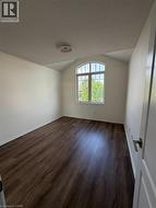 Room featuring a prominent arched window, wood-finish flooring, white baseboards, and a neutral color palette - 
