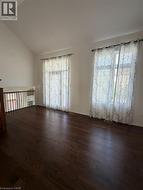 Spacious room with dark wood-finish flooring, two large windows, and a vaulted ceiling - 
