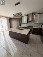 Kitchen featuring a central island with an undermount sink and light-toned countertop - 