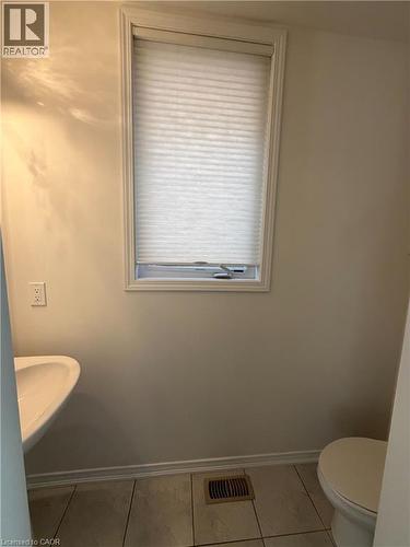 Compact powder room featuring a pedestal sink, white toilet, and window with pleated shade - 235 Apple Hill Crescent, Kitchener, ON 
