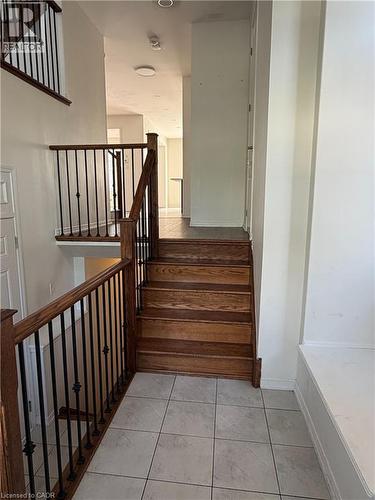 Grand entry featuring a light tile floor, natural wood staircase with wrought iron balusters, and a built-in bench - 235 Apple Hill Crescent, Kitchener, ON 