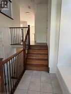 Grand entry featuring a light tile floor, natural wood staircase with wrought iron balusters, and a built-in bench - 