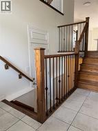 Entryway featuring light-toned tile flooring, a wood staircase with dark iron balusters, and a paneled door - 