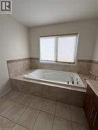 Built-in soaking tub with deck-mounted fixtures, surrounded by neutral-toned tile - 