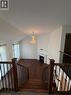 Open-concept living area with vaulted ceilings, a prominent chandelier, wood-finish flooring, and a fireplace with a white mantel - 235 Apple Hill Crescent, Kitchener, ON 