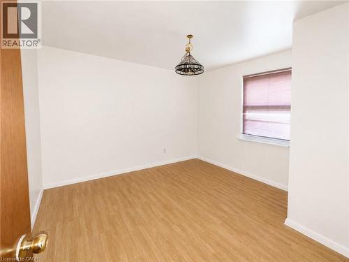 Main Floor Bedroom featuring wood-finish flooring, white walls, and a window with blinds - 83 East 41St Street, Hamilton, ON - Indoor Photo Showing Other Room