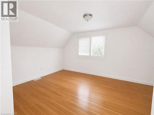 Spacious room featuring wood-finish flooring, white walls, and a sloped ceiling - 83 East 41St Street, Hamilton, ON - Indoor Photo Showing Other Room