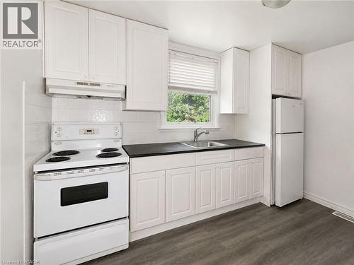 Kitchen featuring white cabinetry, dark countertops, a white electric range, and a white refrigerator - 83 East 41St Street, Hamilton, ON - Indoor Photo Showing Kitchen