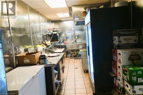 Commercial kitchen featuring stainless steel wall panels, a multi-basin sink, and commercial-grade tiled flooring - 30 Ontario Street S, Kitchener, ON 