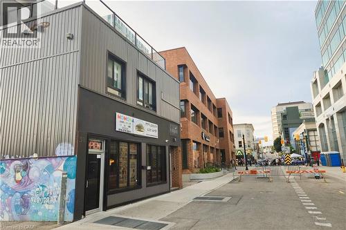Commercial building featuring a dark gray facade with display windows, a black entry door, and corrugated metal siding - 30 Ontario Street S, Kitchener, ON 