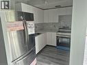 Kitchen featuring white shaker cabinetry, stainless steel appliances, a white marble-look backsplash, white countertops, and wood-finish flooring - 150 Charlton Avenue E Unit# 708, Hamilton, ON 
