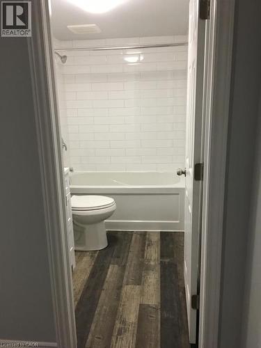 Bathroom featuring a white subway tile shower surround, a white bathtub, and wood-finish flooring - 92 Pattandon Avenue Unit# C, Kitchener, ON - Indoor Photo Showing Bathroom