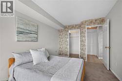 Carpeted room featuring a closet with a built-in shelf and hanging rod, light grey wall paint, and a textured ceiling - 