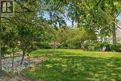 Expansive lawn area featuring mature trees, partial shade, and a decorative rock bed - 