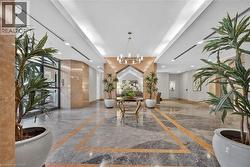 Lobby featuring patterned stone flooring, marble wall accents, a chandelier, and recessed lighting - 