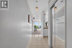 Tiled flooring extending through the hallway, featuring recessed lighting and mirrored closet doors - 