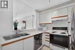 Kitchen featuring white cabinetry with wood-finish accents, a double basin stainless steel sink, and white countertops - 